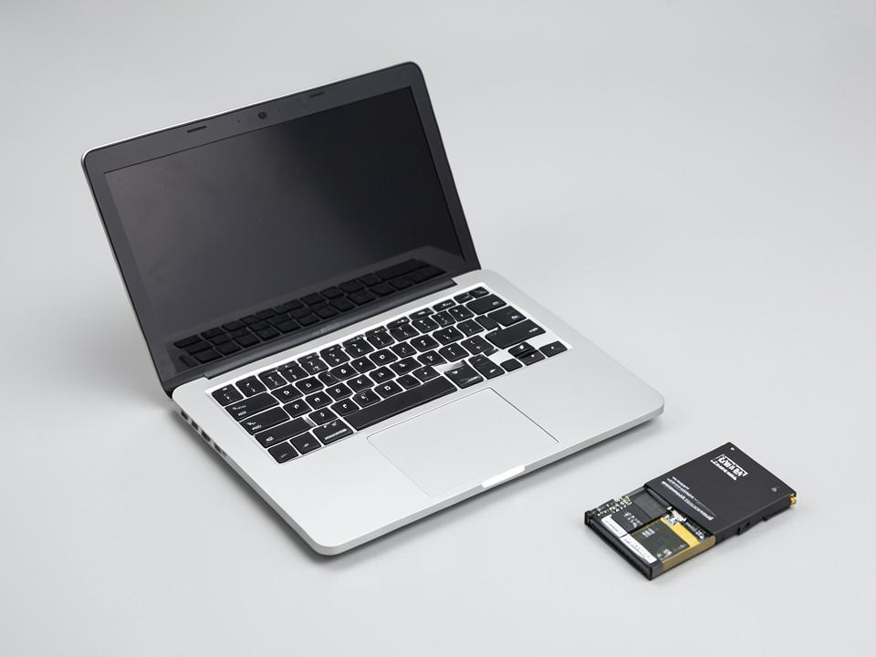 An open laptop beside a replacement battery and repair tool